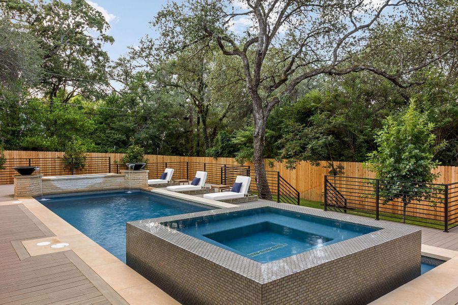 An inviting backyard oasis offers a sparkling pool with an integrated spa, surrounded by a spacious composite deck and privacy fencing.