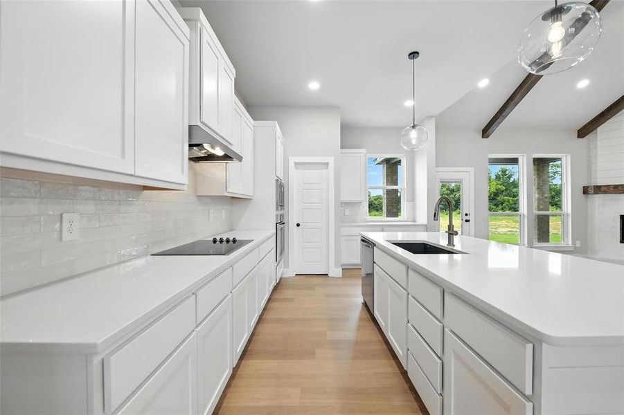 Kitchen featuring under cabinet range hood, black electric cooktop, light countertops, beamed ceiling, and dishwasher Kitchen featuring under cabinet range hood, black electric cooktop, light countertops, beamed ceiling, and dishwasher