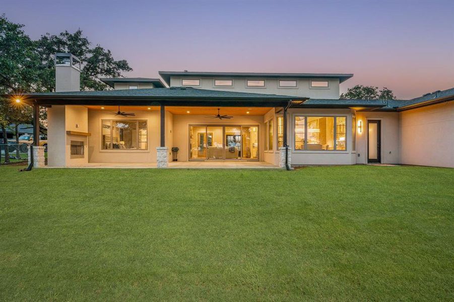 Back house at dusk with a patio area, a yard, and ceiling fan