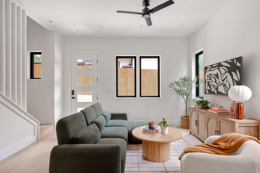 Living room featuring light wood-style flooring and a ceiling fan Living room featuring light wood-style flooring and a ceiling fan