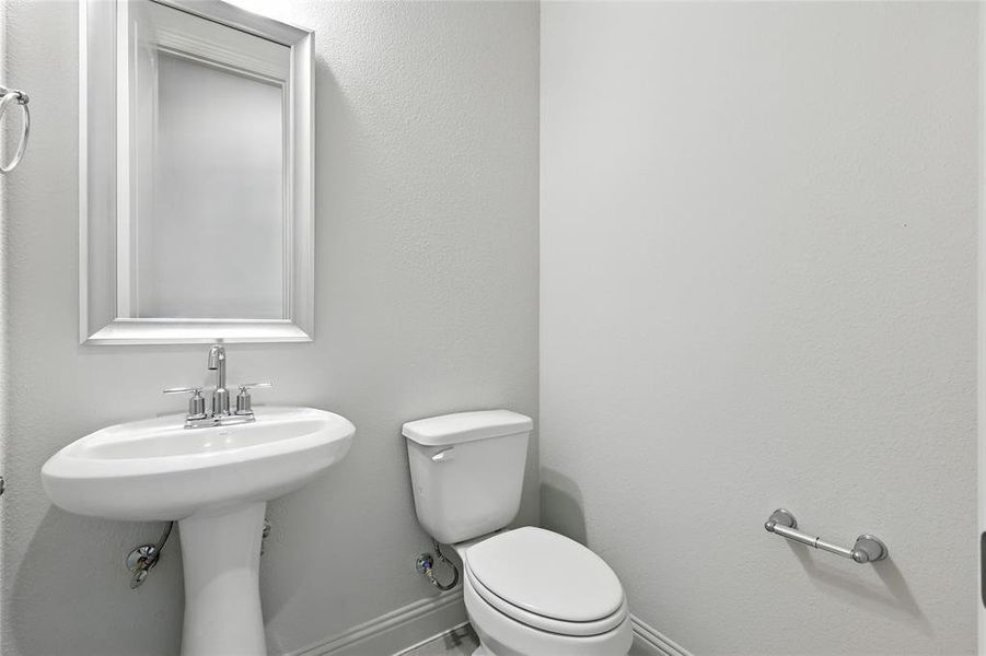 Half bathroom with toilet and a textured wall