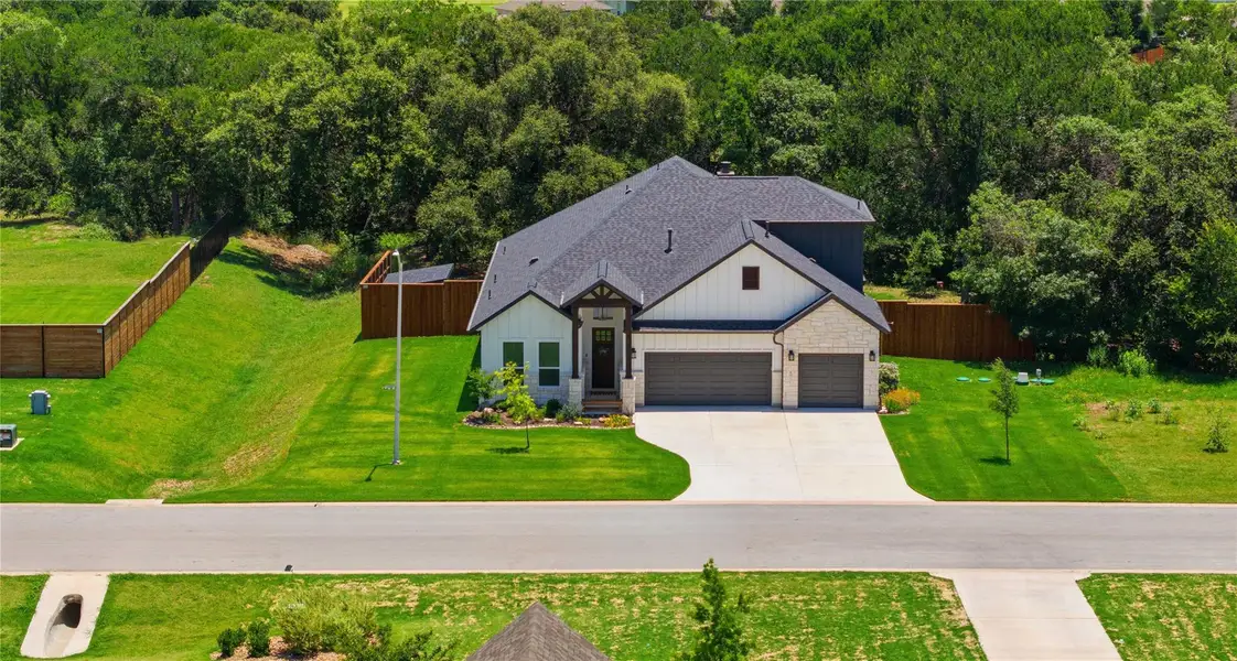 Modern home with a dark roof and light siding is perfectly situated on a well-kept lawn with mature trees. Modern home with a dark roof and light siding is perfectly situated on a well-kept lawn with mature trees.