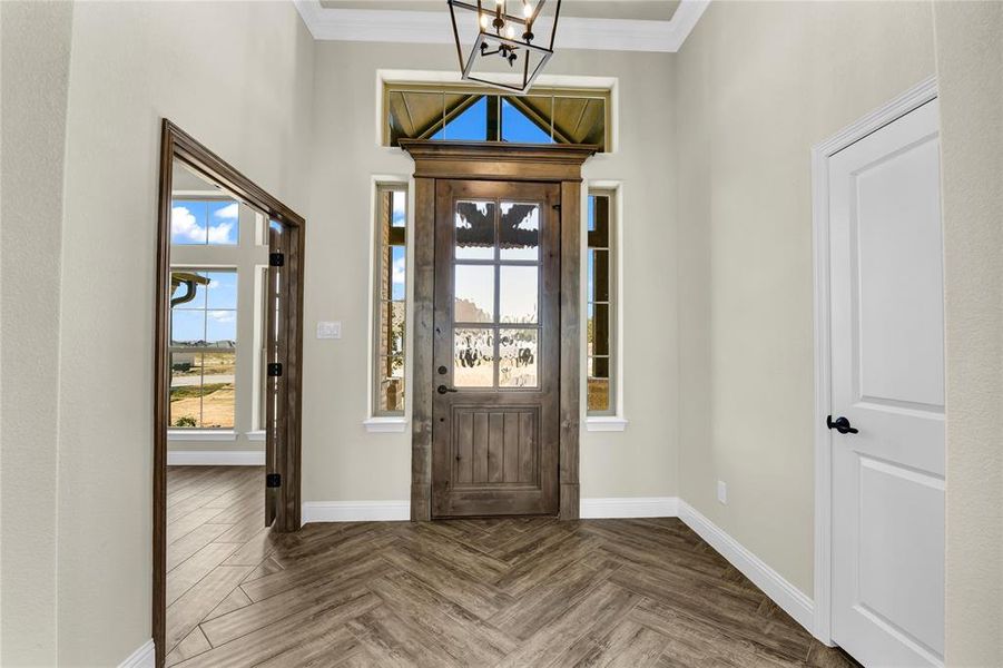 Foyer featuring a notable chandelier, ornamental molding, and dark parquet floors