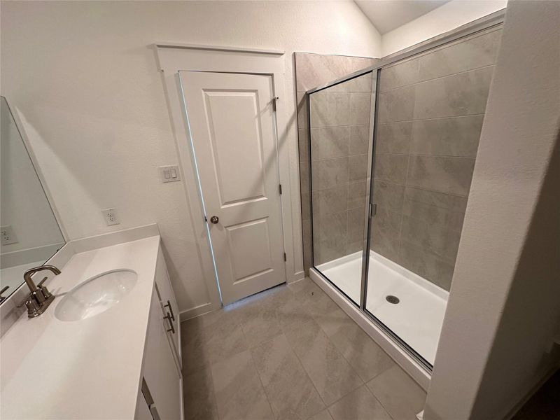 Full bathroom with vanity, a shower stall, light tile patterned floors, and a textured wall Full bathroom with vanity, a shower stall, light tile patterned floors, and a textured wall