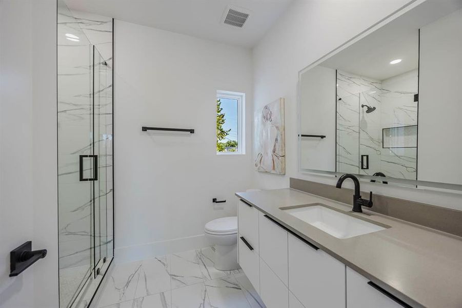 Bathroom featuring vanity, a marble finish shower, and light marble finish floors Bathroom featuring vanity, a marble finish shower, and light marble finish floors