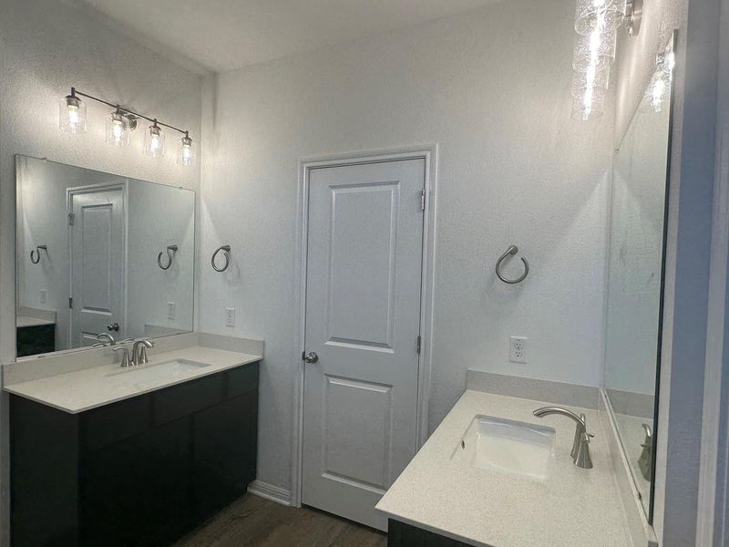 Full bathroom with two vanities and dark wood-type flooring Full bathroom with two vanities and dark wood-type flooring