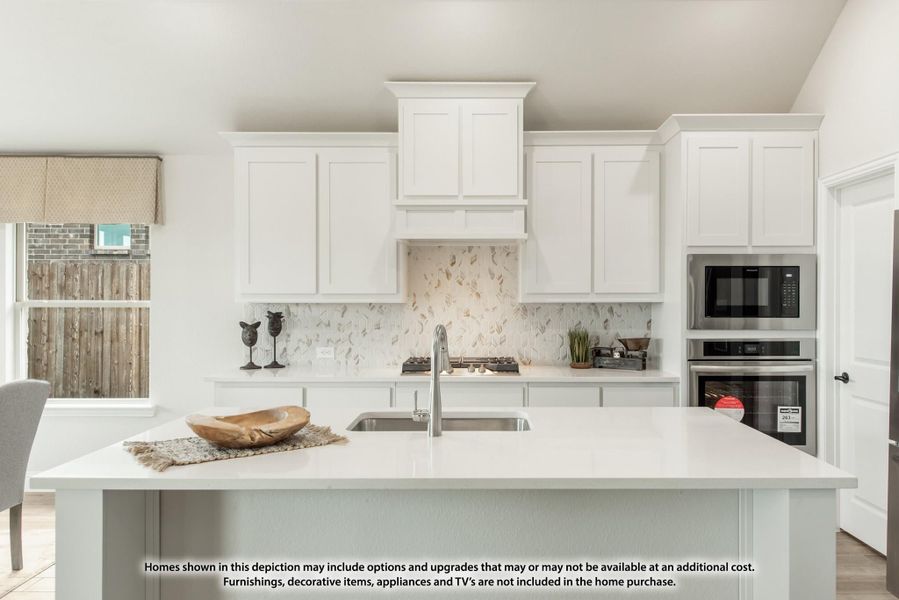 Kitchen with white cabinets, large island with sink, tile backsplash, and stainless steel built-in appliances