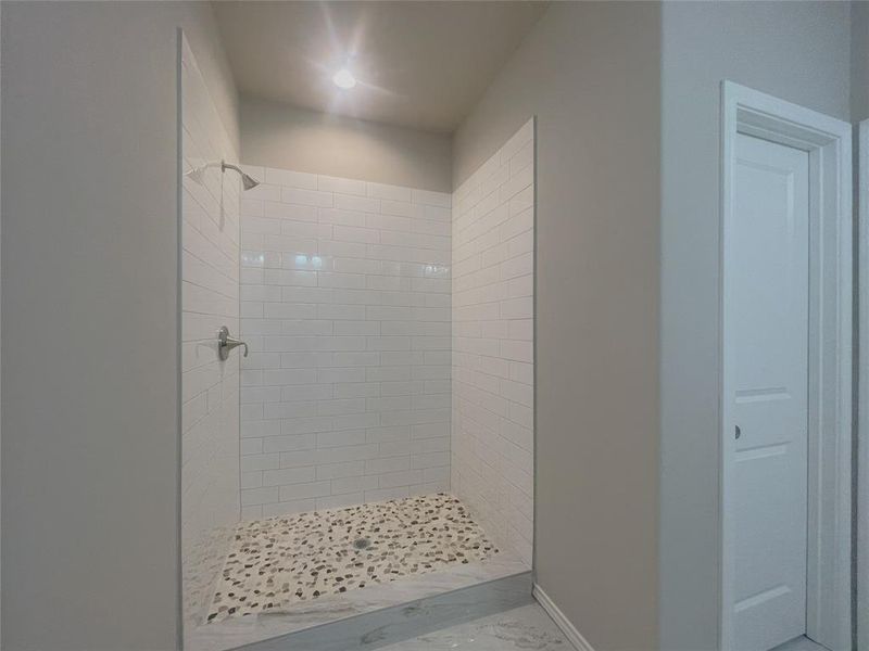 Full bathroom featuring a shower stall and marble finish floors