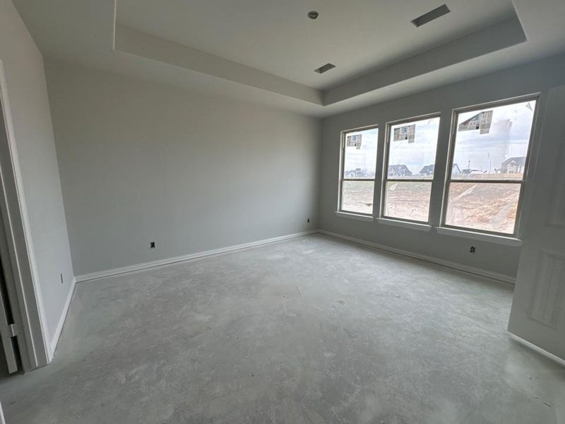 Empty room with a raised ceiling and unfinished concrete floors