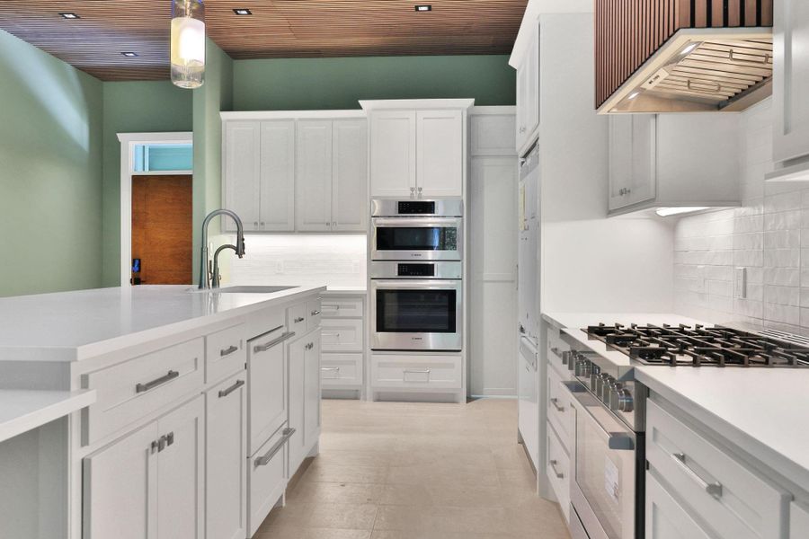 Chef’s kitchen equipped with premium appliances, soft-close cabinetry, gas cooktop, and double ovens and walk in "secret" pantry