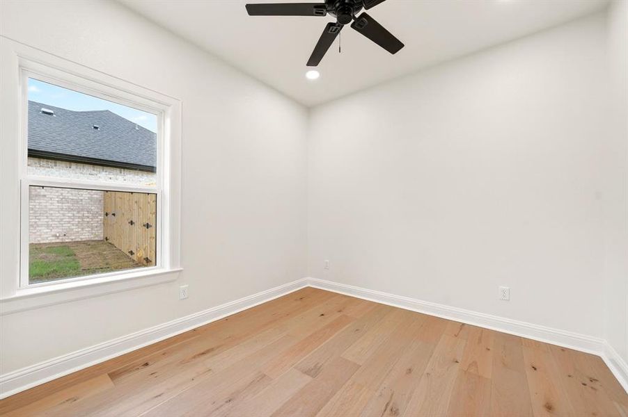 Room featuring wood-finish flooring, crisp white walls, and a contemporary ceiling fan with integrated lighting