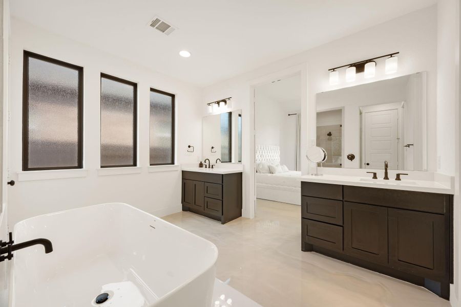 A spacious primary bathroom boasts dual vanities and a freestanding soaking tub, creating a luxurious retreat. A spacious primary bathroom boasts dual vanities and a freestanding soaking tub, creating a luxurious retreat.
