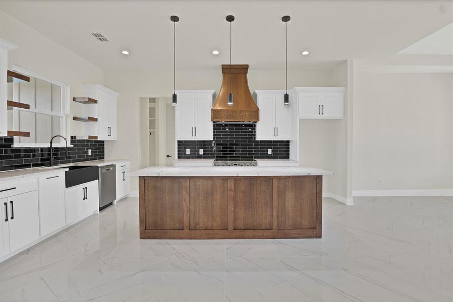 Kitchen featuring a center island, custom range hood, white cabinets, decorative light fixtures, and stainless steel dishwasher