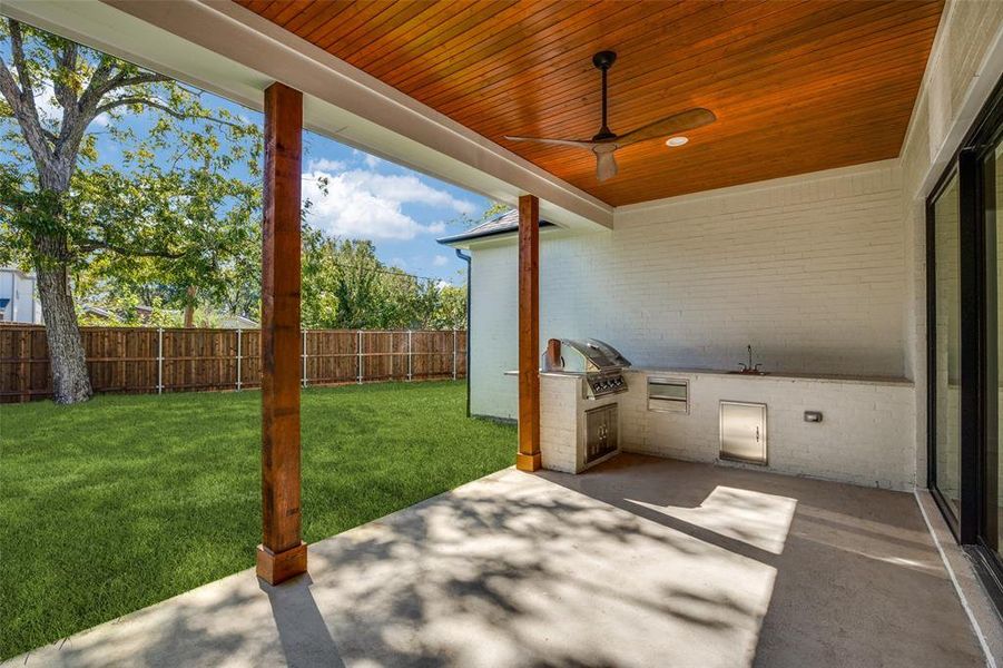Fenced backyard featuring a patio and an outdoor kitchen Fenced backyard featuring a patio and an outdoor kitchen