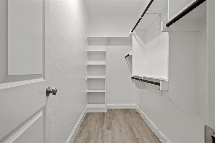 Spacious closet with light hardwood / wood-style flooring