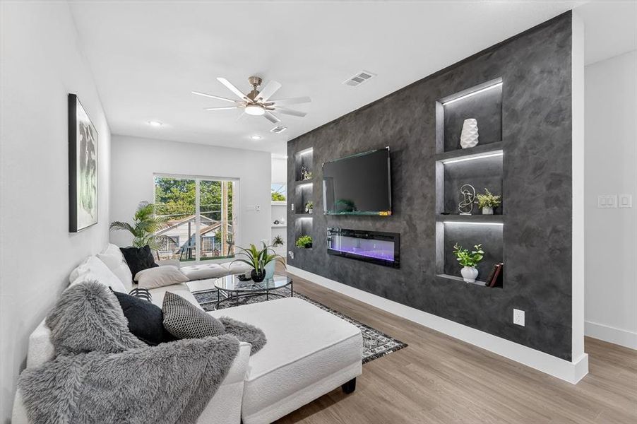 Accent wall featuring an electric fireplace, television mount, and illuminated display niches