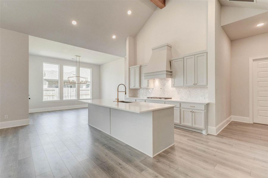 Spacious, open-concept kitchen and dining area with high ceilings and abundant natural light. Modern cabinetry, a large central island with sleek countertops, and elegant flooring.