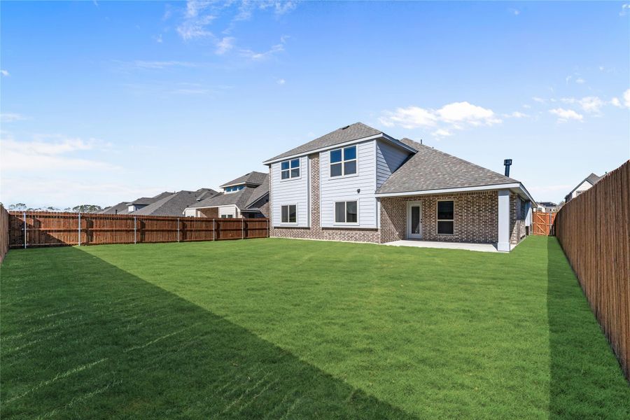 Two-story brick and siding home with large fenced backyard and green lawn