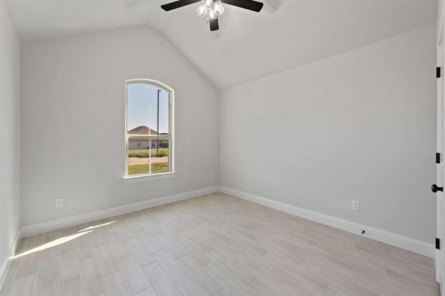 Empty room featuring wood tiled floors, vaulted ceiling, and a ceiling fan