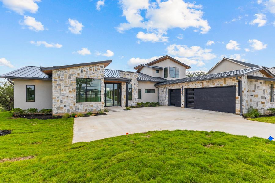 Modern stone and stucco facade with a broad driveway and sleek garage doors defines this distinctive residence. Modern stone and stucco facade with a broad driveway and sleek garage doors defines this distinctive residence.