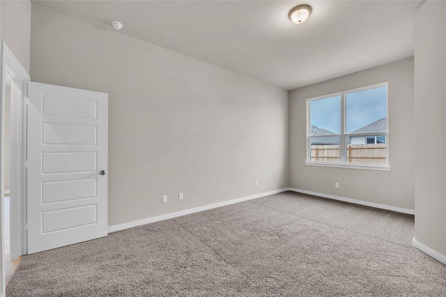 Empty room with light colored carpet and baseboards