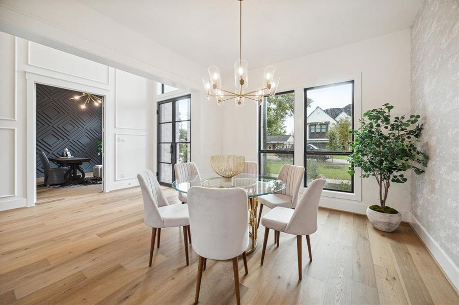 The light and bright dining room features a stylish chandelier, a wallpapered accent wall, and is adjacent to the butlers pantry.