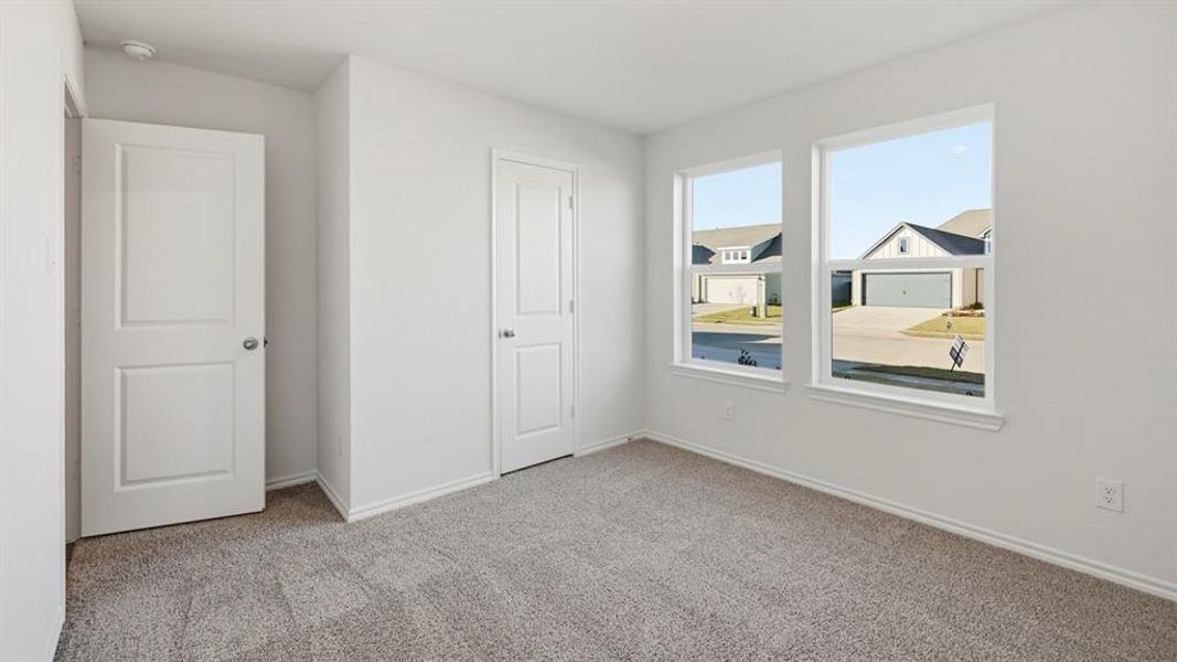 Unfurnished bedroom with light colored carpet and baseboards