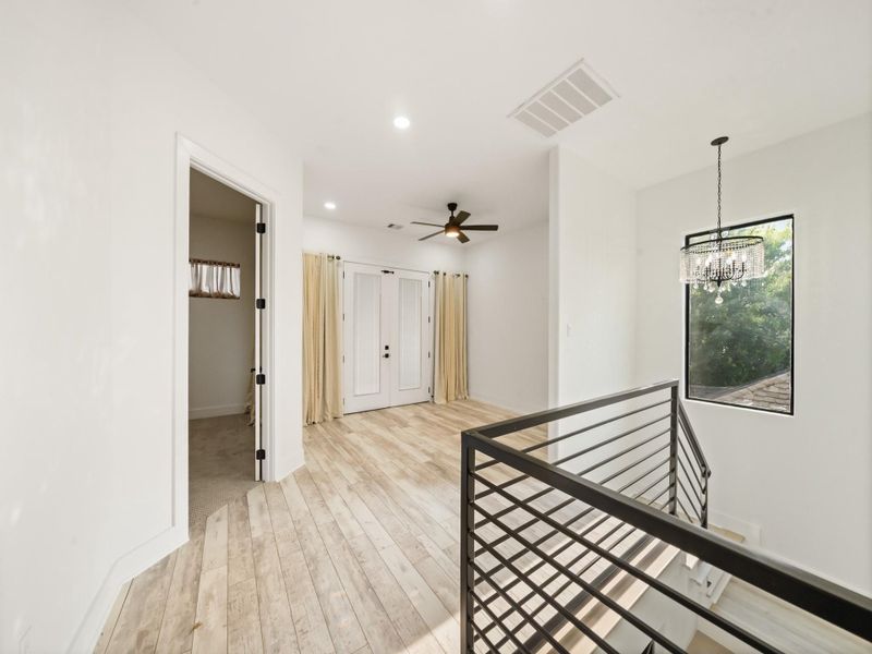 Second floor loft or game-room, wrought iron guard-rail, decrearive ceiling light fixture, luxury vinyl plank flooring, high ceilings, and 8 ft. doors