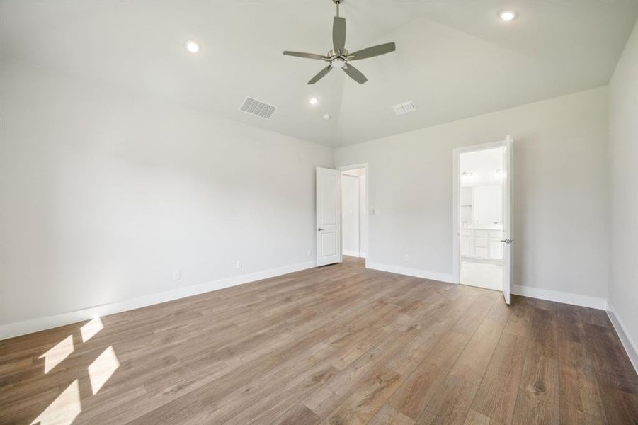 Unfurnished bedroom with ensuite bath, ceiling fan, high vaulted ceiling, and light hardwood / wood-style floors