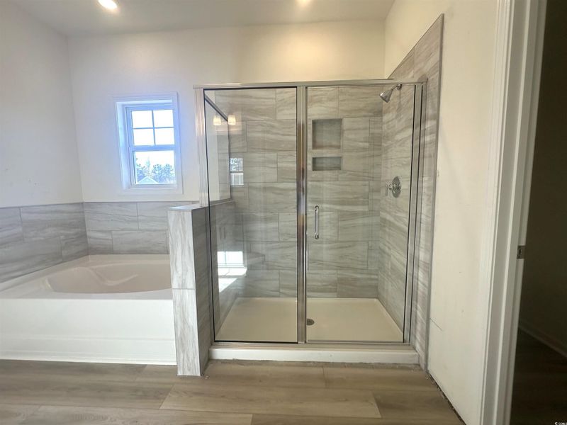 Bathroom with wood finished floors, a bath, and a stall shower