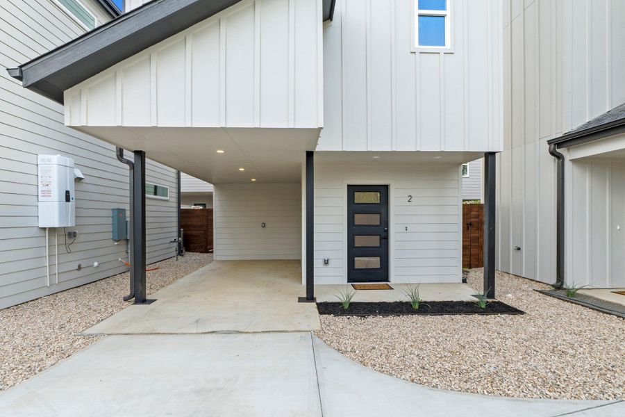 Entrance to property with board and batten siding and a carport
