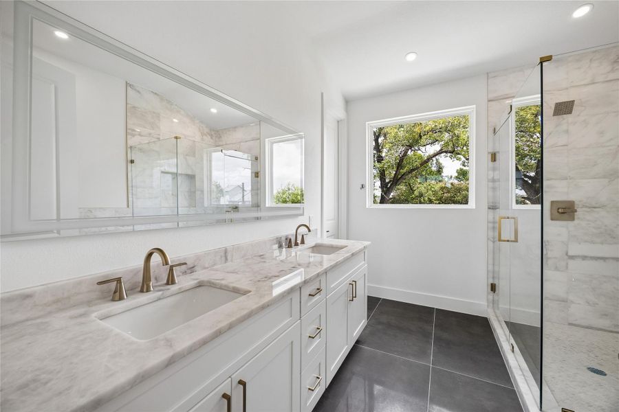 Double sinks and gorgeous marble accents adorn the frameless shower.