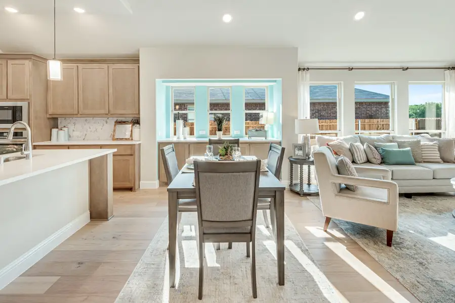 Open-concept living area with dining table, light wood cabinets, and hardwood floors connecting to a living room