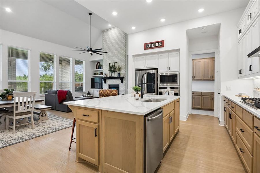 Spacious kitchen featuring a central island with a sink and dishwasher, white countertops, and light wood-finish cabinetry Spacious kitchen featuring a central island with a sink and dishwasher, white countertops, and light wood-finish cabinetry