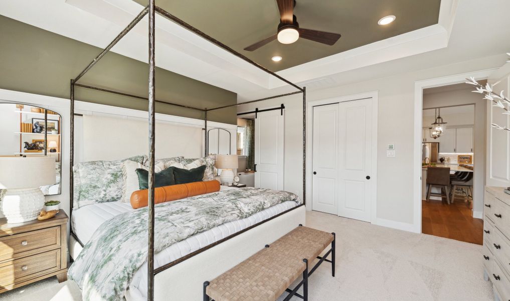 Primary suite with feature wall, tray ceiling and barn door to bath Primary suite with feature wall, tray ceiling and barn door to bath