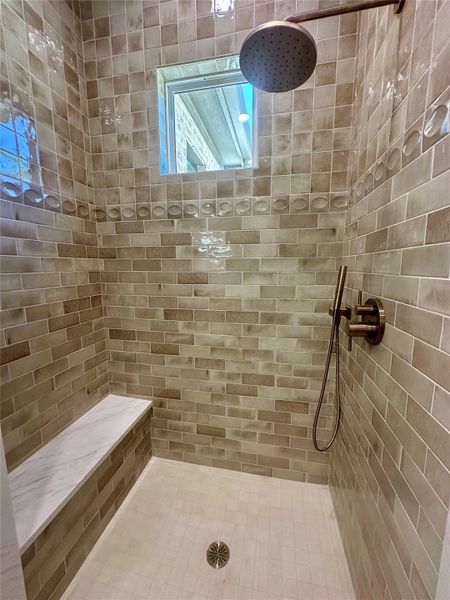 Glistening wall tiles surround a modern walk-in shower featuring a built-in bench and rain showerhead.