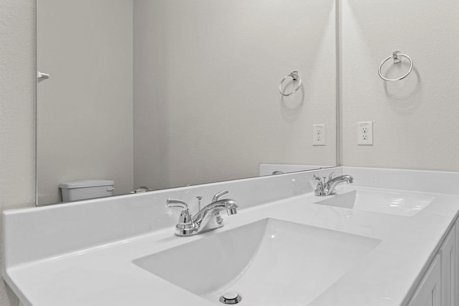 Another view of the primary bath showcasing the elegant dual sinks, bright lighting, and stylish fixtures that complement the home’s modern design. Another view of the primary bath showcasing the elegant dual sinks, bright lighting, and stylish fixtures that complement the home’s modern design.