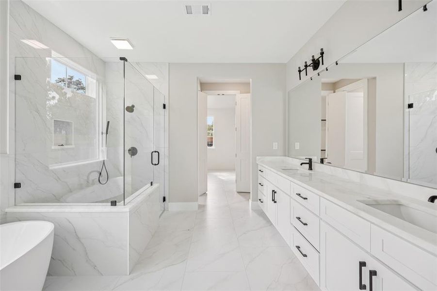 Full bath featuring double vanity, a marble finish shower, a freestanding tub, and light marble finish flooring