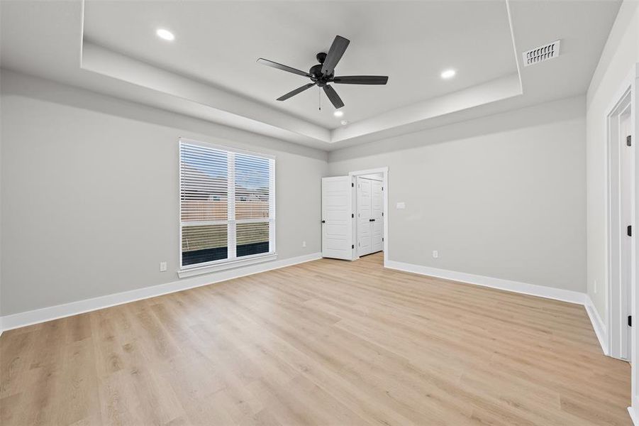 Unfurnished bedroom featuring light wood-type flooring, a ceiling fan, a raised ceiling, and recessed lighting Unfurnished bedroom featuring light wood-type flooring, a ceiling fan, a raised ceiling, and recessed lighting