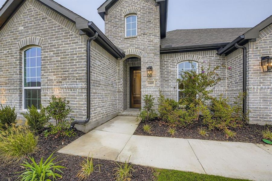 Doorway to property with brick siding and a shingled roof
