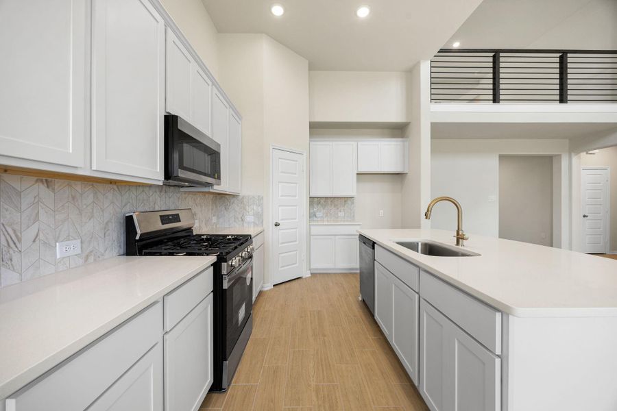 This bright and modern chef's kitchen is designed for both style and functionality. It showcases clean lines with abundant white shaker-style cabinetry, sleek white countertops, and a chic marble-look tile backsplash extending to the upper cabinets. The kitchen also comes equipped with stainless steel appliances, an undermount sink with stylish gold/brass-toned faucet and a pantry all overlooking the Family and Dining rooms. This bright and modern chef's kitchen is designed for both style and functionality. It showcases clean lines with abundant white shaker-style cabinetry, sleek white countertops, and a chic marble-look tile backsplash extending to the upper cabinets. The kitchen also comes equipped with stainless steel appliances, an undermount sink with stylish gold/brass-toned faucet and a pantry all overlooking the Family and Dining rooms.