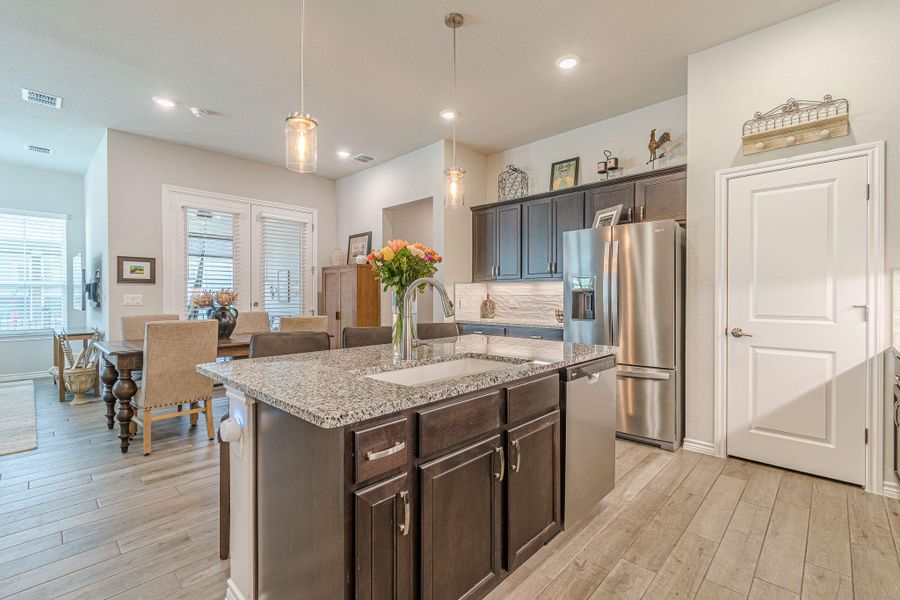 Kitchen featuring a sink, appliances with stainless steel finishes, light wood-style flooring, dark brown cabinetry, and recessed lighting
