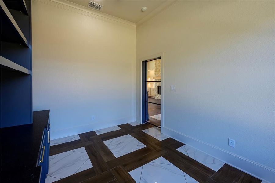 Unfurnished bedroom featuring ornamental molding and dark marble finish floors