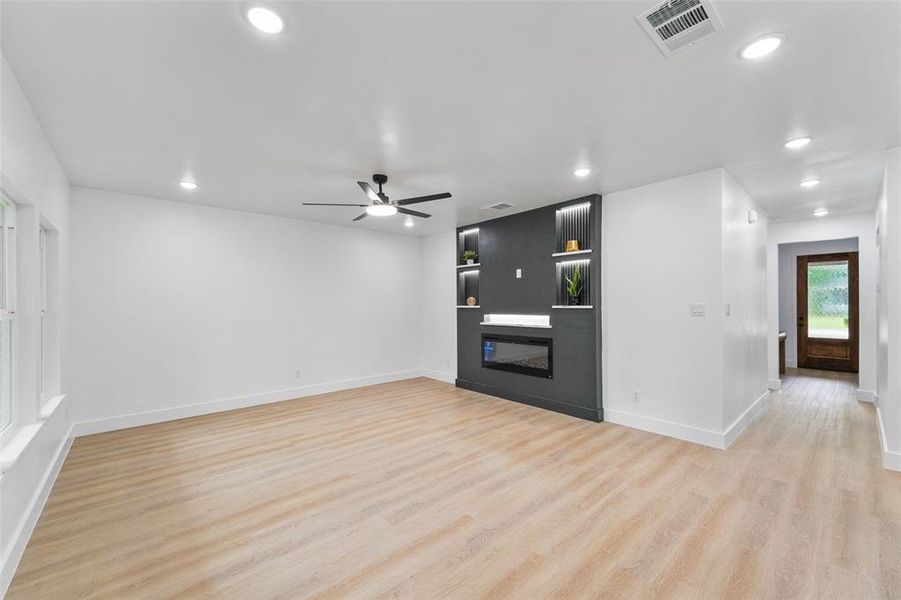 Spacious interior featuring light wood-finish flooring, recessed lighting, and a contemporary ceiling fan Spacious interior featuring light wood-finish flooring, recessed lighting, and a contemporary ceiling fan