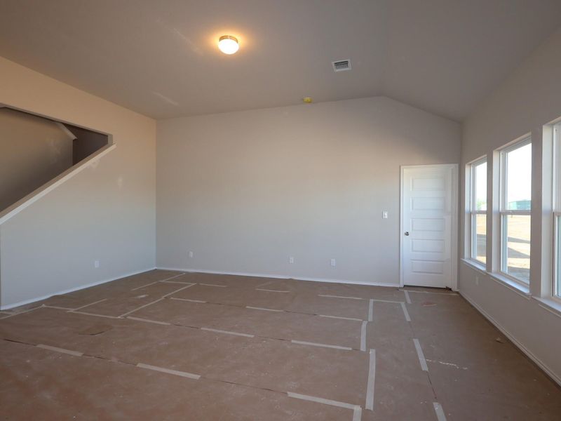 Spare room featuring vaulted ceiling and baseboards