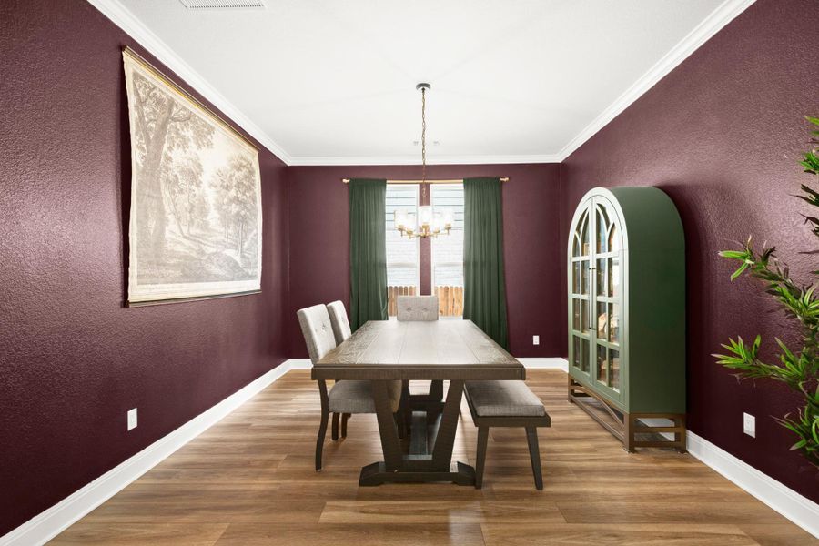 Dining room with a textured wall, light wood finished floors, ornamental molding, and a chandelier Dining room with a textured wall, light wood finished floors, ornamental molding, and a chandelier