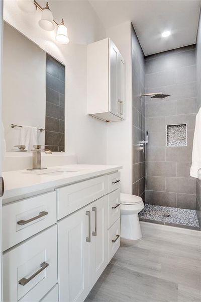Full bath featuring vanity, a stall shower, and light wood-style floors Full bath featuring vanity, a stall shower, and light wood-style floors
