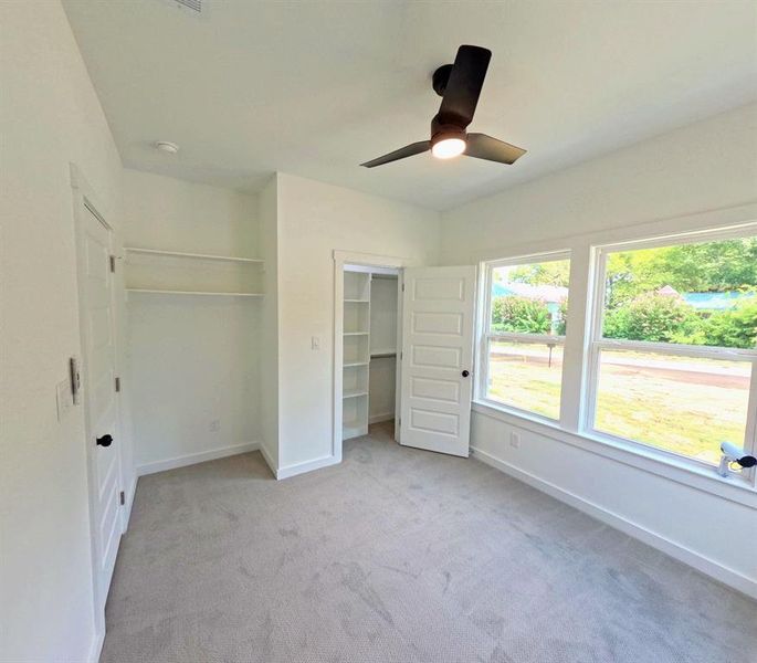 Unfurnished bedroom featuring light colored carpet and a ceiling fan Unfurnished bedroom featuring light colored carpet and a ceiling fan