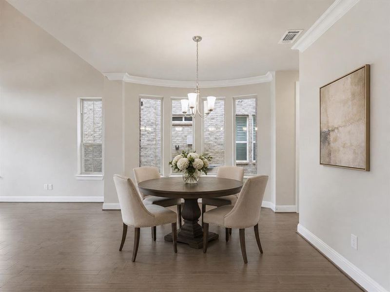Dining area featuring wood-finish flooring, a bay window with multiple vertical windows, and a ceiling-mounted chandelier Dining area featuring wood-finish flooring, a bay window with multiple vertical windows, and a ceiling-mounted chandelier