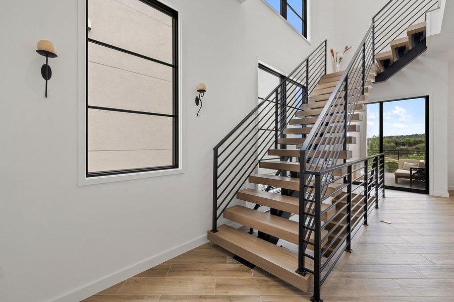 Modern open-riser staircase with wood-finish treads and black metal railings